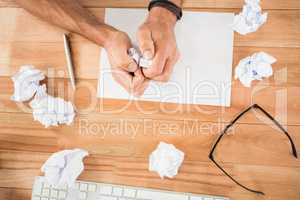 Hands crumpling paper on wooden desk