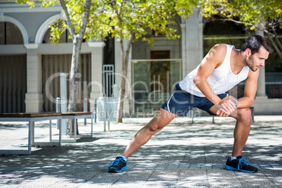 Handsome athlete stretching his leg