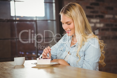 Smiling blonde eating cake and having coffee