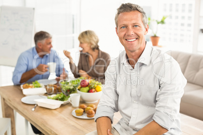 Smiling casual businessman sitting on table at lunch