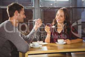 Smiling friends enjoying coffee and cake together