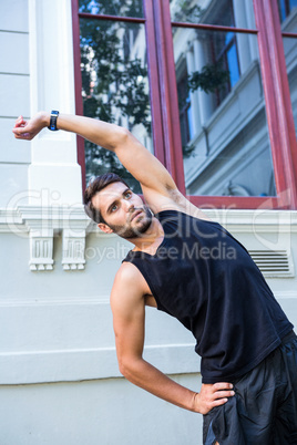 Handsome athlete stretching in front of a building