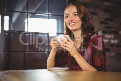 Smiling brunette enjoying cup of coffee