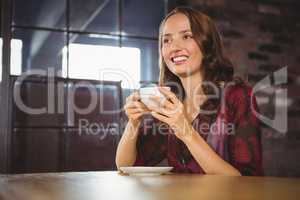 Smiling brunette enjoying cup of coffee