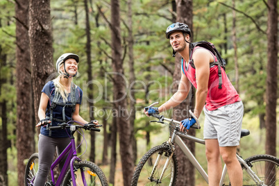 Young happy couple on bikes looking away