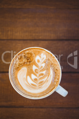 Cup of cappuccino with coffee art on wooden table