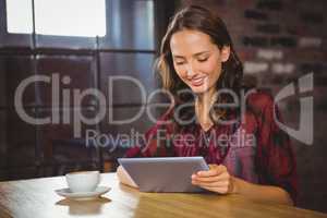 Smiling brunette having coffee and using tablet