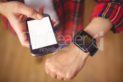 Pretty hipster using her smartphone and smartwatch