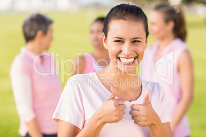Smiling brunette wearing pink for breast cancer in front of frie Smiling brunette wearing pink for breast cancer in front of frie