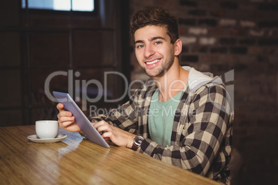 Smiling hipster sitting and using tablet computer