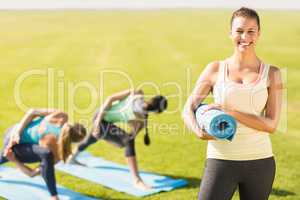 Smiling sporty brunette in front of friends doing exercises