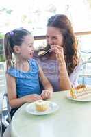 Mother and daughter enjoying cakes at cafe terrace