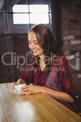 Smiling brunette enjoying cup of coffee