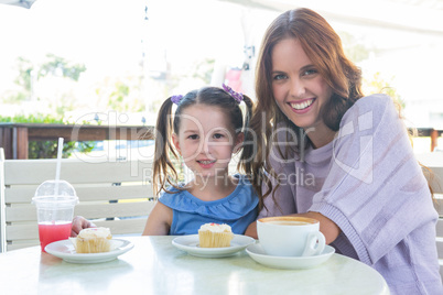 Mother and daughter enjoying cakes at cafe terrace