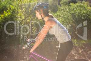 Athletic brunette mountain biking on path