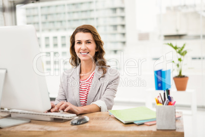 Smiling casual businesswoman working with computer