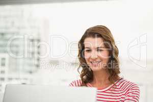 Smiling casual businesswoman using laptop