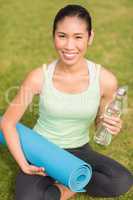 Sporty woman sitting with exercise mat and water bottle