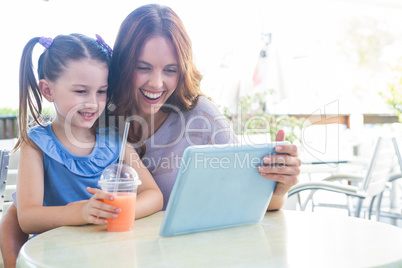 Mother and daughter using tablet at cafe terrace