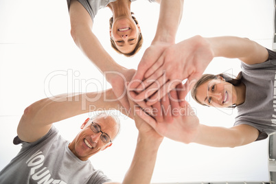 Smiling volunteers putting hands together
