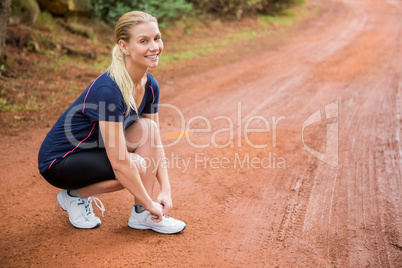 Smiling athletic blonde tying her shoelace