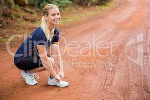 Smiling athletic blonde tying her shoelace
