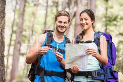 Happy hikers looking at camera holding map and compass