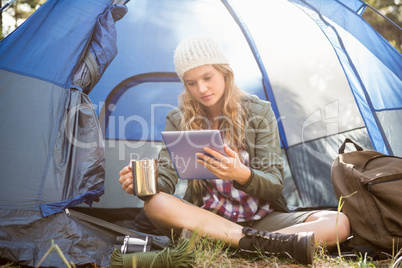 Pretty blonde camper using tablet and holding cup