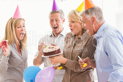 Casual business people blowing birthday candles