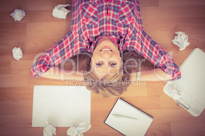 Smiling woman lying on floor surrounded by papers