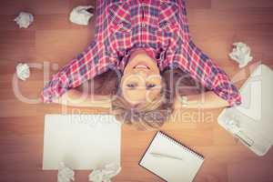 Smiling woman lying on floor surrounded by papers