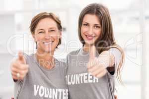 Smiling female volunteers doing thumbs up