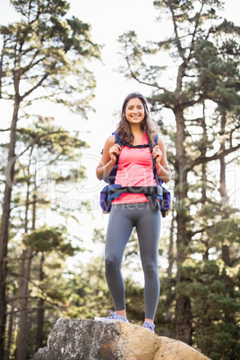 Young happy jogger standing on rock looking at camera