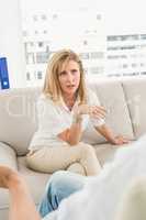 Unhappy woman sitting on couch and talking to therapist