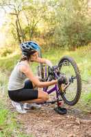 Athletic brunette repairing her mountain bike