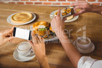 Two people taking picture of foods