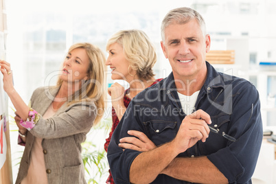 Businessman with arms crossed with his team behind