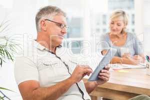 Serious businessman scrolling on a tablet
