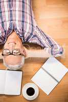 Smiling man lying on floor surrounded by office items