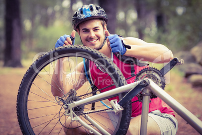 Happy handsome biker repairing bike showing thumbs up