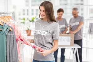 Smiling female volunteer choosing clothes