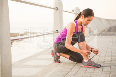 Fit woman tying shoelace at promenade