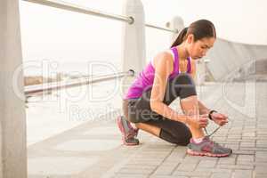 Fit woman tying shoelace at promenade