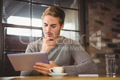 Handsome man focusing on tablet computer