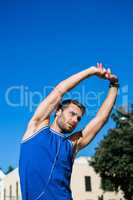 Handsome athlete stretching against blue sky
