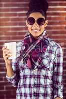 A female hipster holding a cup of coffee