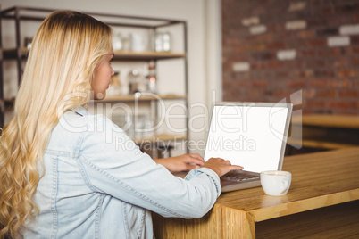 Rear view of blonde typing on laptop