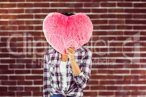 Young woman holding up heart-shaped pillow