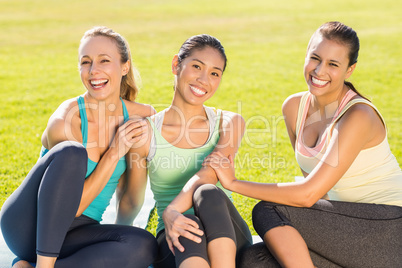 Smiling sporty women sitting on ground