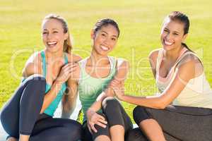 Smiling sporty women sitting on ground